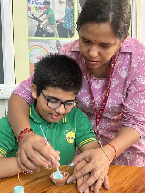 Painting diyas with a teacher's help
